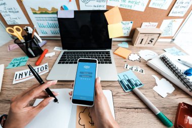 Kiev, Ukrayna - 23 Temmuz 2019: boş ekranlı yazı ve dizüstü bilgisayar ile yapışkan notlar yakın skype uygulaması ile akıllı telefon tutan kadın kırpılmış görünümü 