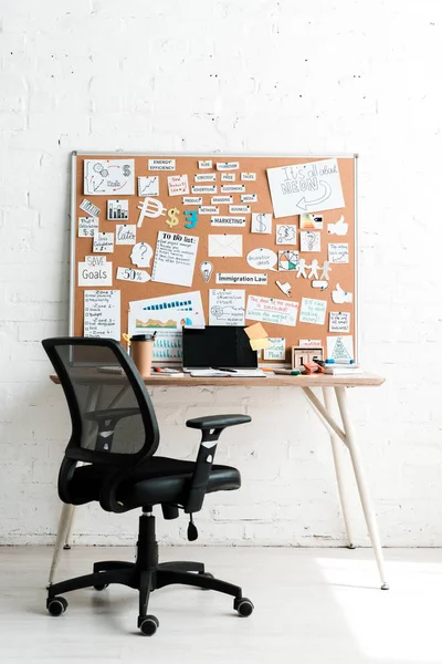 notice board with lettering on sticky notes near table and chair