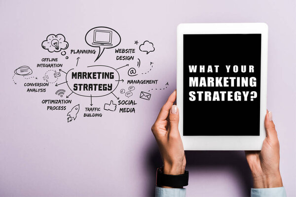 обрезанный взгляд женщины, держащей цифровой планшет с тем, что ваша маркетинговая стратегия надпись на фиолетовый
 
