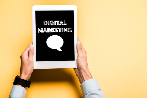 обрезанный вид женщины, держащей цифровой планшет с цифровыми маркетинговыми письмами на оранжевом
 