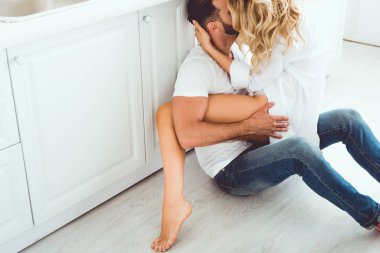 mutfakta yerde otururken sarılma ve öpüşme genç çift kırpılmış görünümü