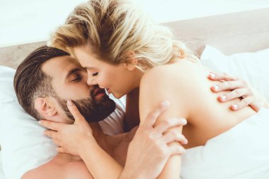 yatakta yatarken yakışıklı erkek arkadaşı kucaklayan güzel, şehvetli kadın