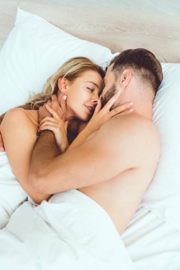mutlu genç çift kucaklayan ve yatakta yatarken öpüşme