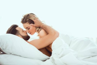 genç çift yatakta yatan, kucaklayan ve kapalı gözlerle öpüşme