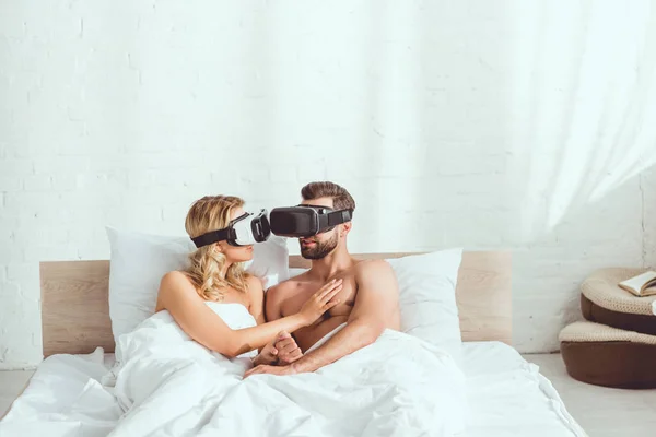 Jovem Casal Abraçando Enquanto Deitado Cama Usando Fones Ouvido Realidade — Fotografia de Stock