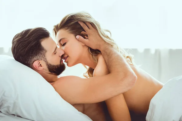 Bonito Jovem Beijando Bela Namorada Enquanto Deitado Cama — Fotografia de Stock