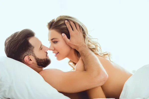 幸せな若いカップルは ベッドに横たわっている間 抱きしめ お互いを見つめる — ストック写真