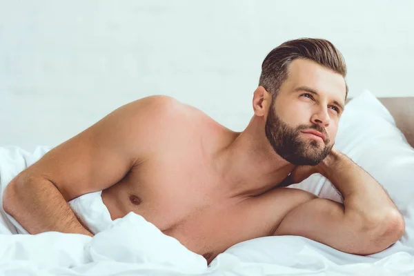 Yakışıklı Gömleksiz Seksi Adam Yatakta Yatan Uzağa Bakıyor — Stok fotoğraf