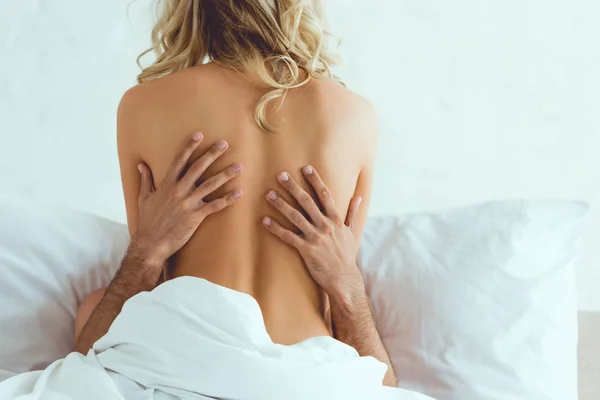 back view of young woman embracing with boyfriend in bedroom