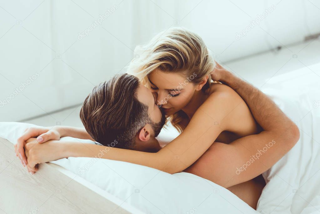 beautiful young woman hugging boyfriend while lying in bed at home