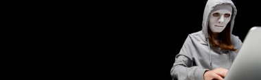 siyah izole dizüstü bilgisayar kullanarak maske anonim internet troll panoramik çekim