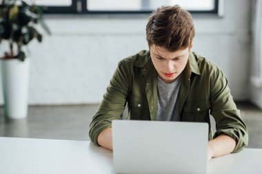 odaklanmış genç çocuk masada oturan ve evde dizüstü bilgisayar kullanarak
