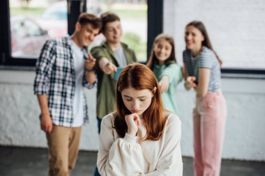 selective focus of group of teenagers bullying sad girl clipart
