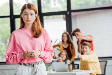 öğrenci grubu akıllı telefon ile üzgün kız zorbalık