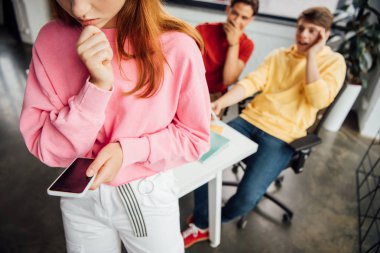 sınıf arkadaşları okulda ona gülerken akıllı telefon tutan üzgün kız kısmi görünümü