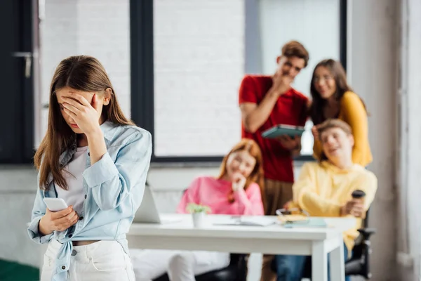 Groep Schoolkinderen Lachen Verdrietig Meisje Met Smartphone — Stockfoto