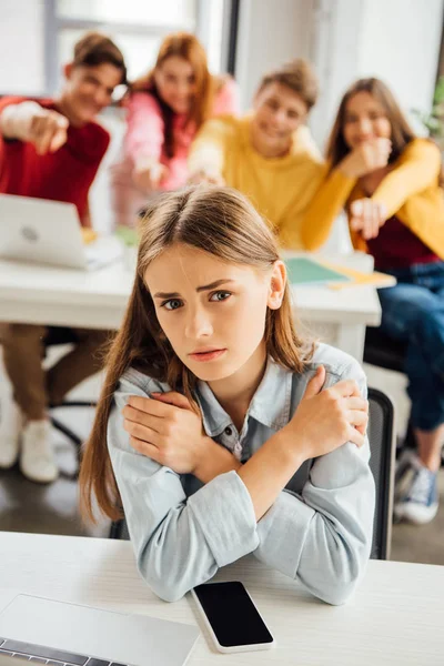 前景で悲しい女の子をいじめながら笑う小学生 — ストック写真