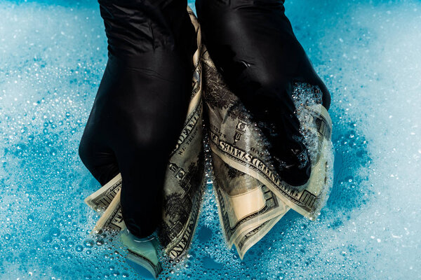cropped view of man in black rubber gloves washing dollar banknotes 