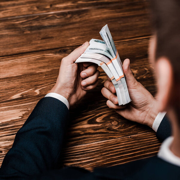 selective focus of man holding russian money near wooden table 
