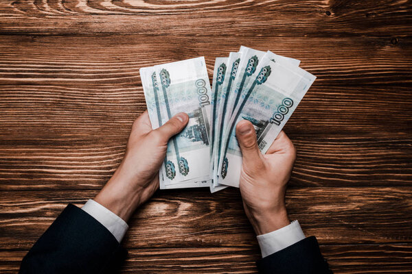 top view of man counting russian money near table 