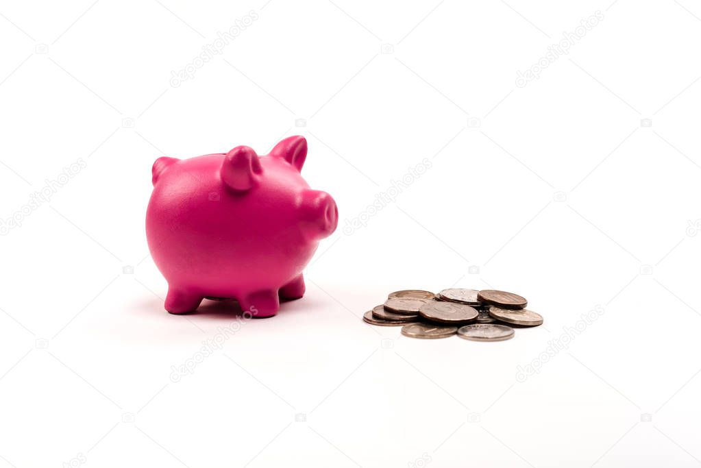 pink piggy bank near silver and golden coins on white 