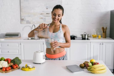 mutlu sporcu meyve ve sebze yakınında cam içine smoothie döken 