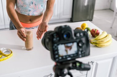 smoothie ve dijital kamera ile cam yakınında gesturing kız seçici odak 