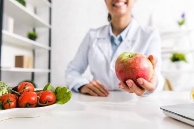 sebze yakınında lezzetli elma tutan beslenme uzmanı kırpılmış görünümü 