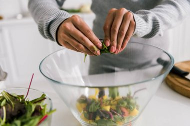 cam kase yakınında yeşil yaprakları tutan kadın kırpılmış görünümü 