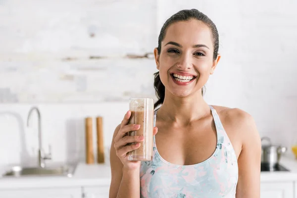 happy sportive woman holding glass with smoothie