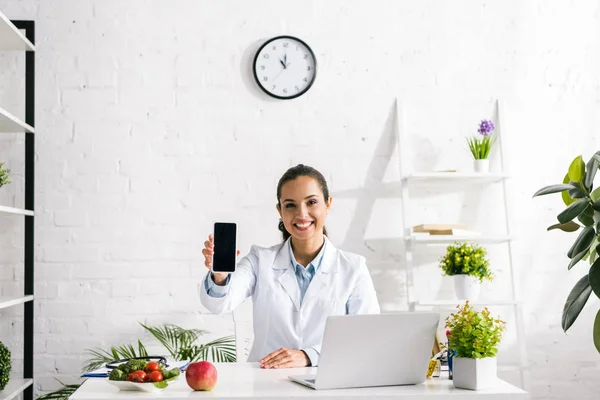 Happy Nutritionist Holding Smartphone Blank Screen Laptop — Stock Photo, Image