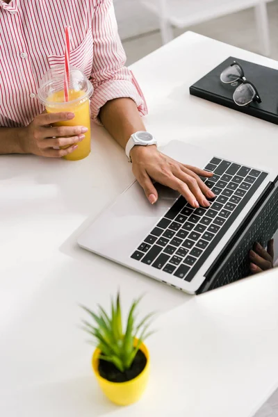 Vista Cortada Menina Usando Laptop Enquanto Segurando Copo Plástico Com — Fotografia de Stock