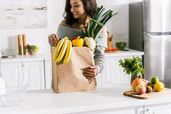 happy girl looking at tasty bananas in paper bag