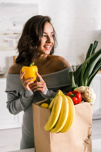快乐的女人拿着黄色的辣椒在杂货店附近 — 图库照片
