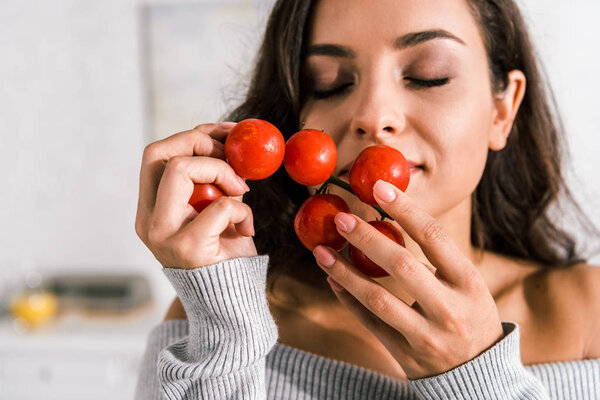 привлекательная женщина, нюхающая спелые помидоры черри
 