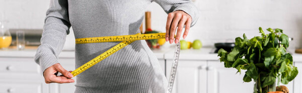 panoramic shot of young woman measuring waist 