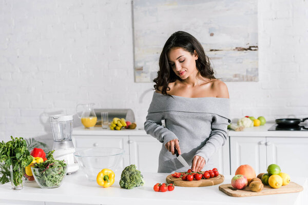 beautiful girl holding knife near cherry tomatoes 