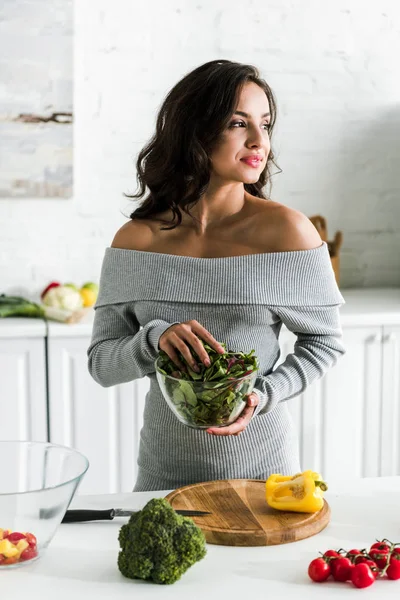 野菜の近くに立ち 緑とボウルを保持する魅力的な女性 — ストック写真