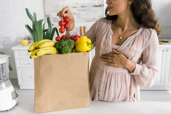 Vista Recortada Mujer Embarazada Sosteniendo Tomates Cherry Mientras Toca Vientre — Foto de Stock