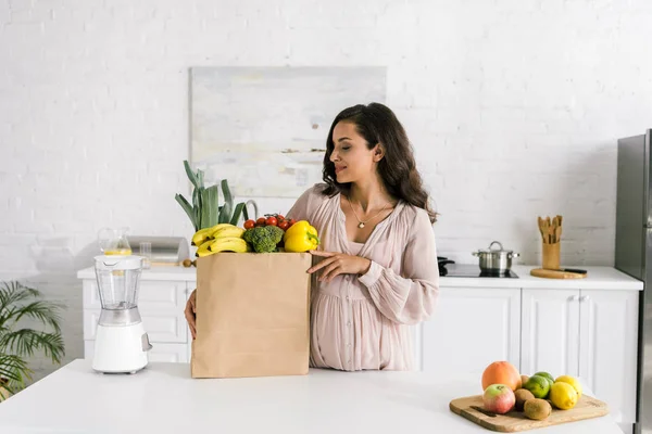 Schwangere Blickt Auf Papiertüte Mit Lebensmitteln — Stockfoto