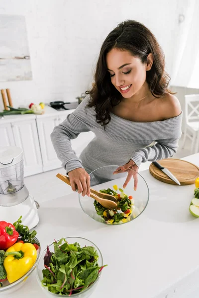 Glad Pige Blande Frisk Salat Nær Grøntsager Derhjemme - Stock-foto