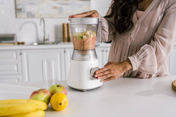cropped view of pregnant woman preparing smoothie in blender 