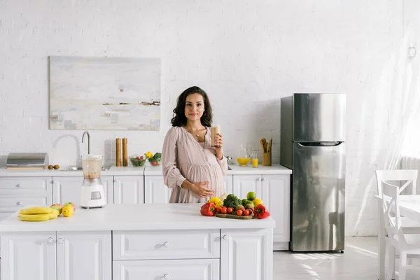 Atractiva Mujer Embarazada Sosteniendo Vidrio Con Batido Cerca Mesa —  Fotos de Stock