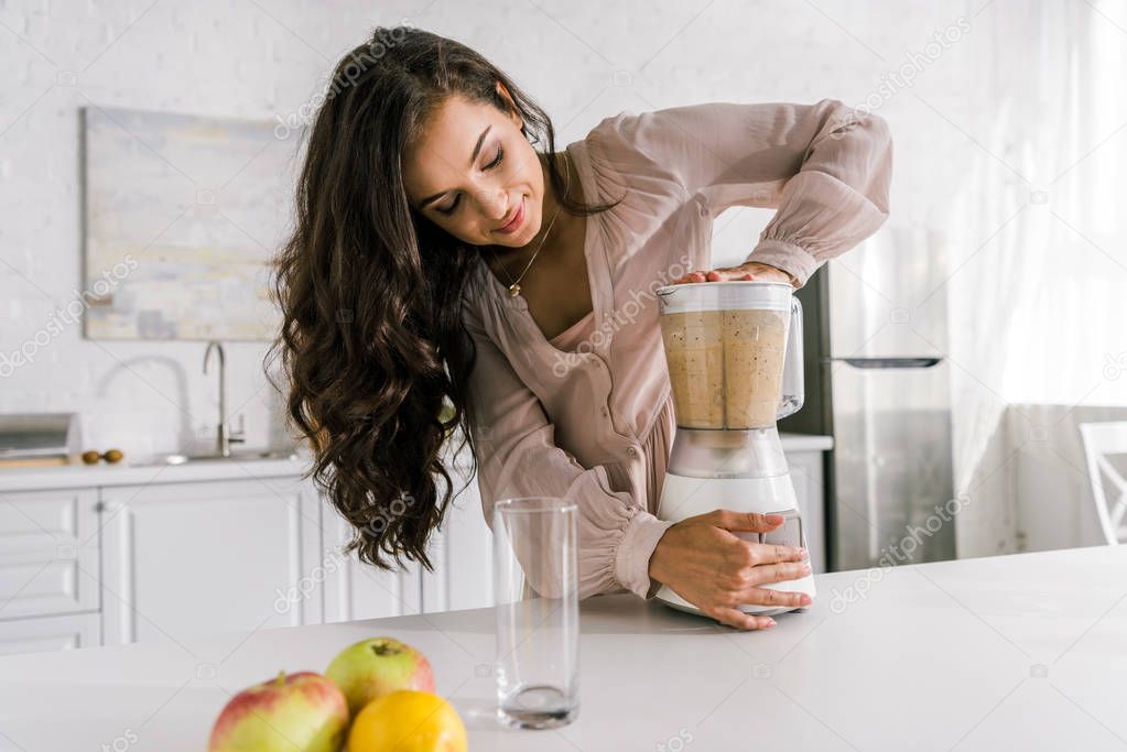 attractive pregnant woman preparing tasty smoothie in blender 