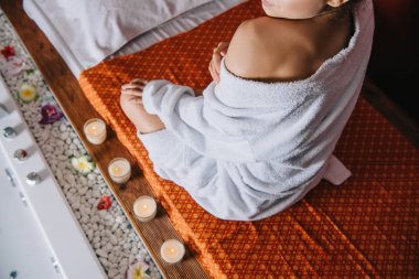 spa salonunda masaj minye sinde oturan bornoz kadın kırpılmış görünümü