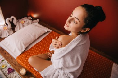 spa salonunda masaj minyesinde oturan bornoz çekici kadın yüksek açı görünümü