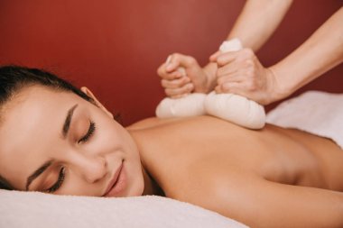 spa kadın bitkisel topları ile geri masaj yapıyor masör kırpılmış görünümü