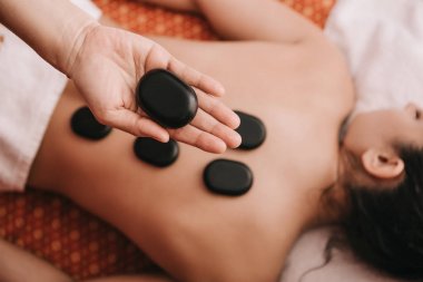 spa salonunda kadına sıcak taş masajı yapan masör kırpılmış görünümü 