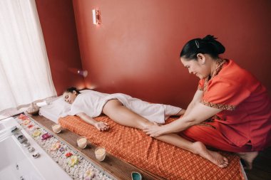 asyalı masör spa salonunda kadına ayak masajı yapıyor 