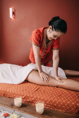 asyalı masör spa salonunda kadına ayak masajı yapıyor 